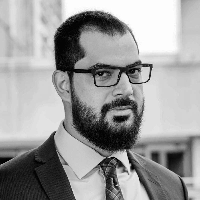 A man with a beard wearing glasses and a suit