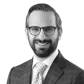 A black and white photo of a man wearing a suit and tie